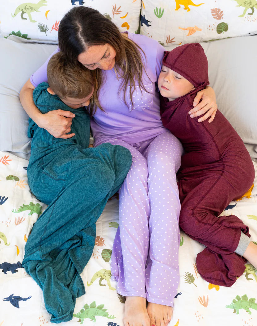 Woman sitting on a bed with two sleeping children